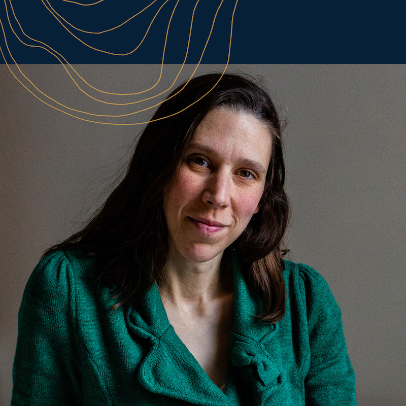 Headshot of Anouk in an emerald green blazer with a navy banner and gold waves across the top